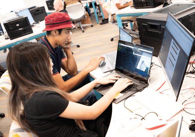 Students work together on computers in a computer lab.