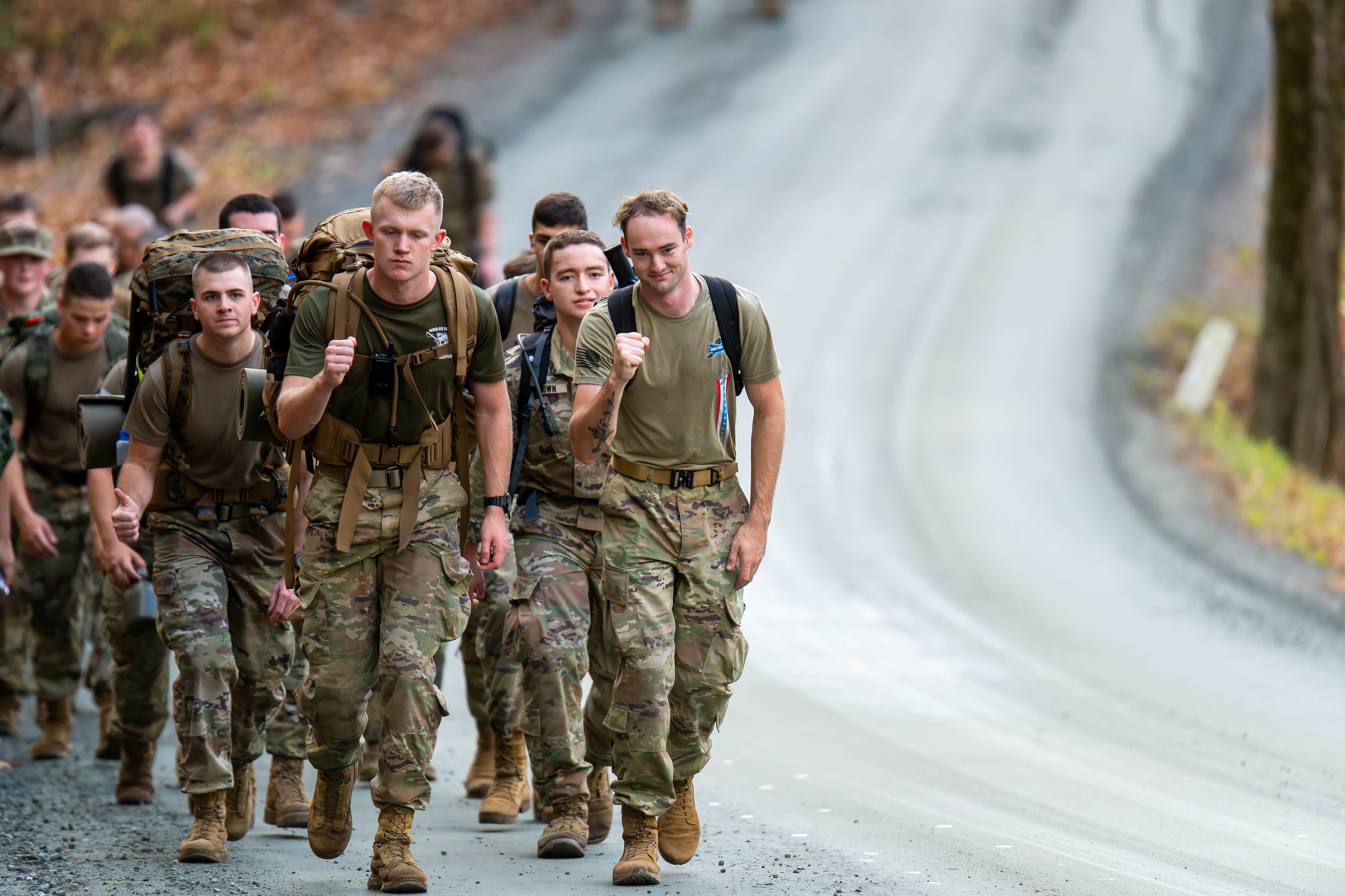 Cadets participating in the Norwich University Legacy March, marching on a road surrounded by trees and fallen leaves