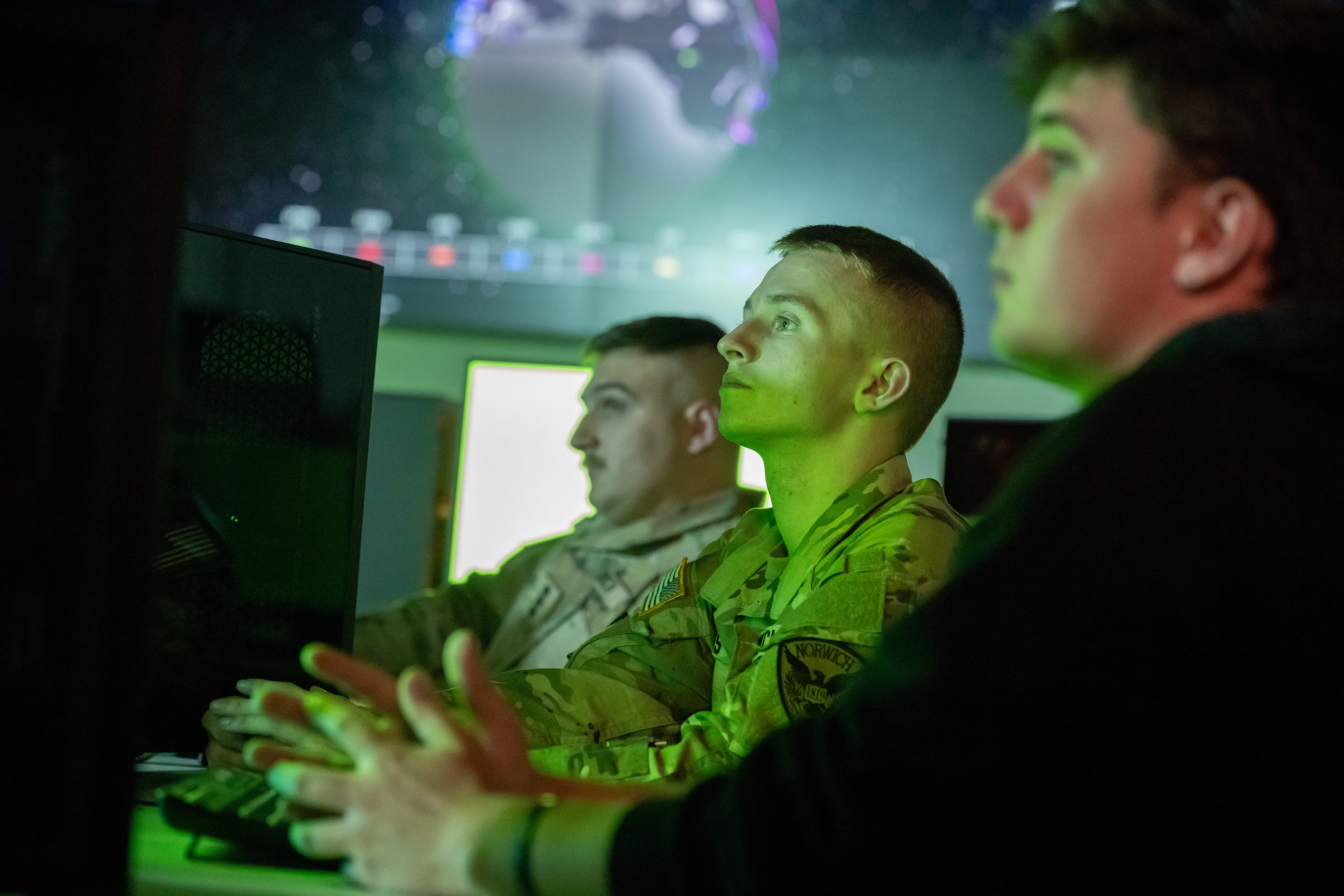 Three students in front of a computer in the Norwich University Cyber War Room.