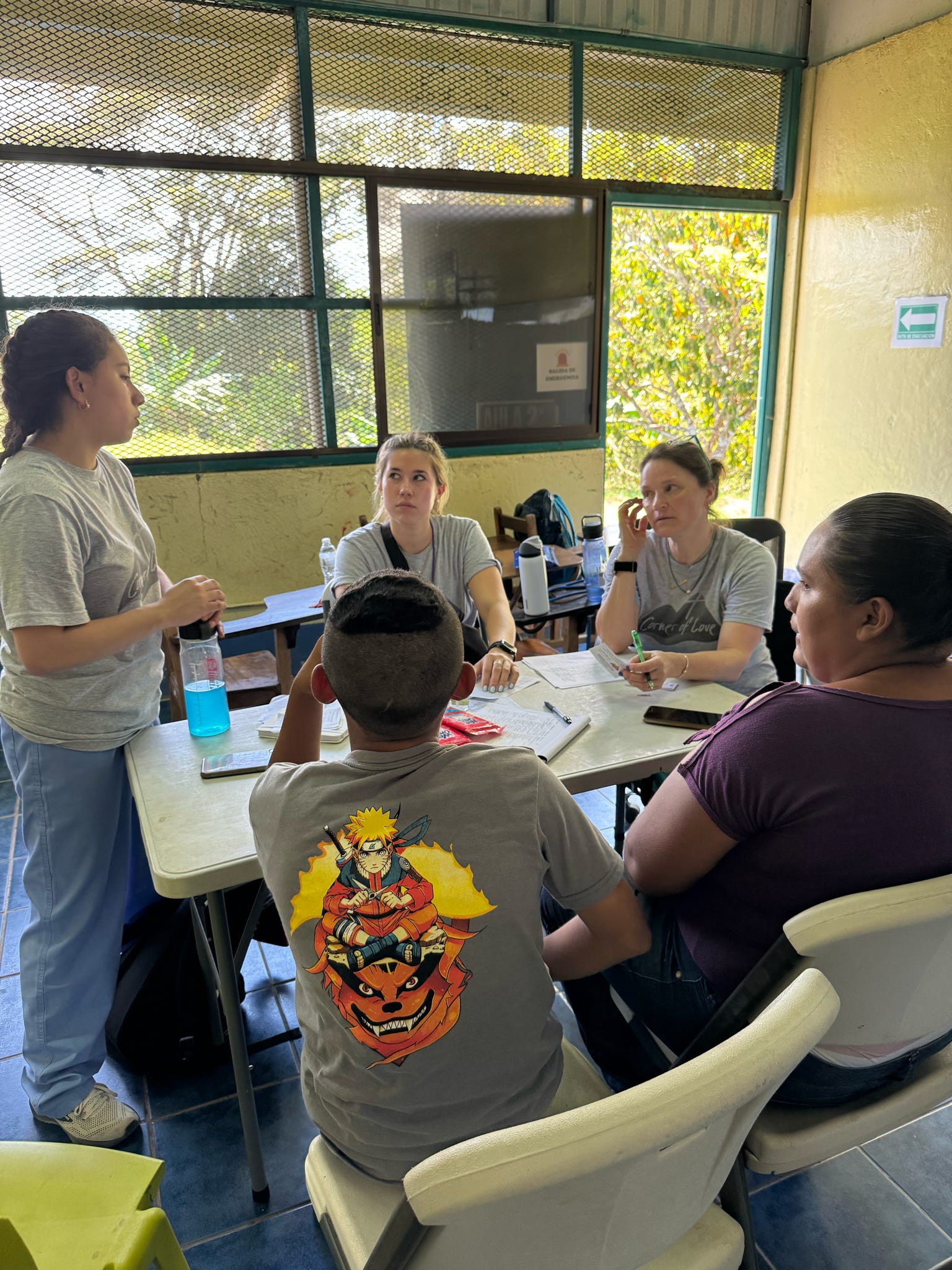 A group of Norwich University School of Nursing students sitting around a table in a screened room with trees outside