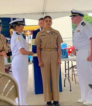 U.S. Navy officers in uniform participating in a formal ceremony under a tent.
