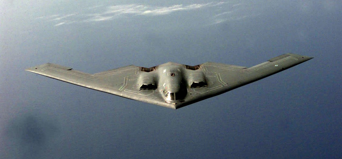 A B-2 Spirit stealth bomber in flight against a cloudy sky.