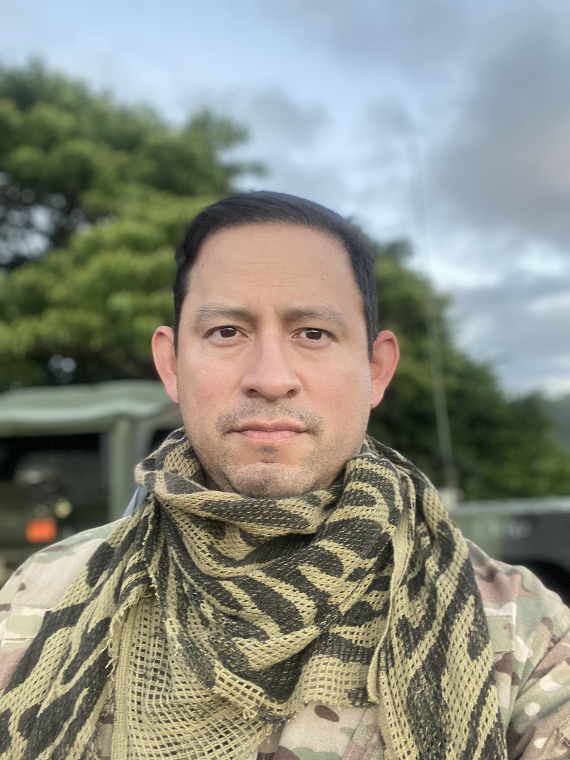 A headshot of Daniel Fienco in camouflage, while outdoors.
