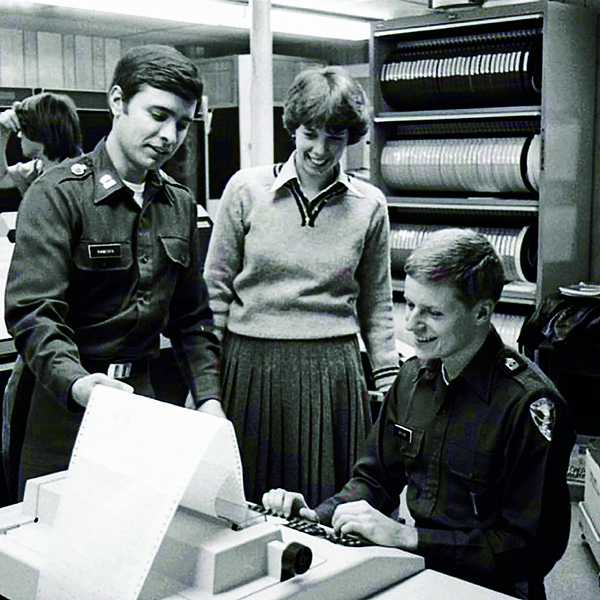 Period B+W photo of FRANK VANECEK H10 in front of tape drive computer terminal with green bar paper
