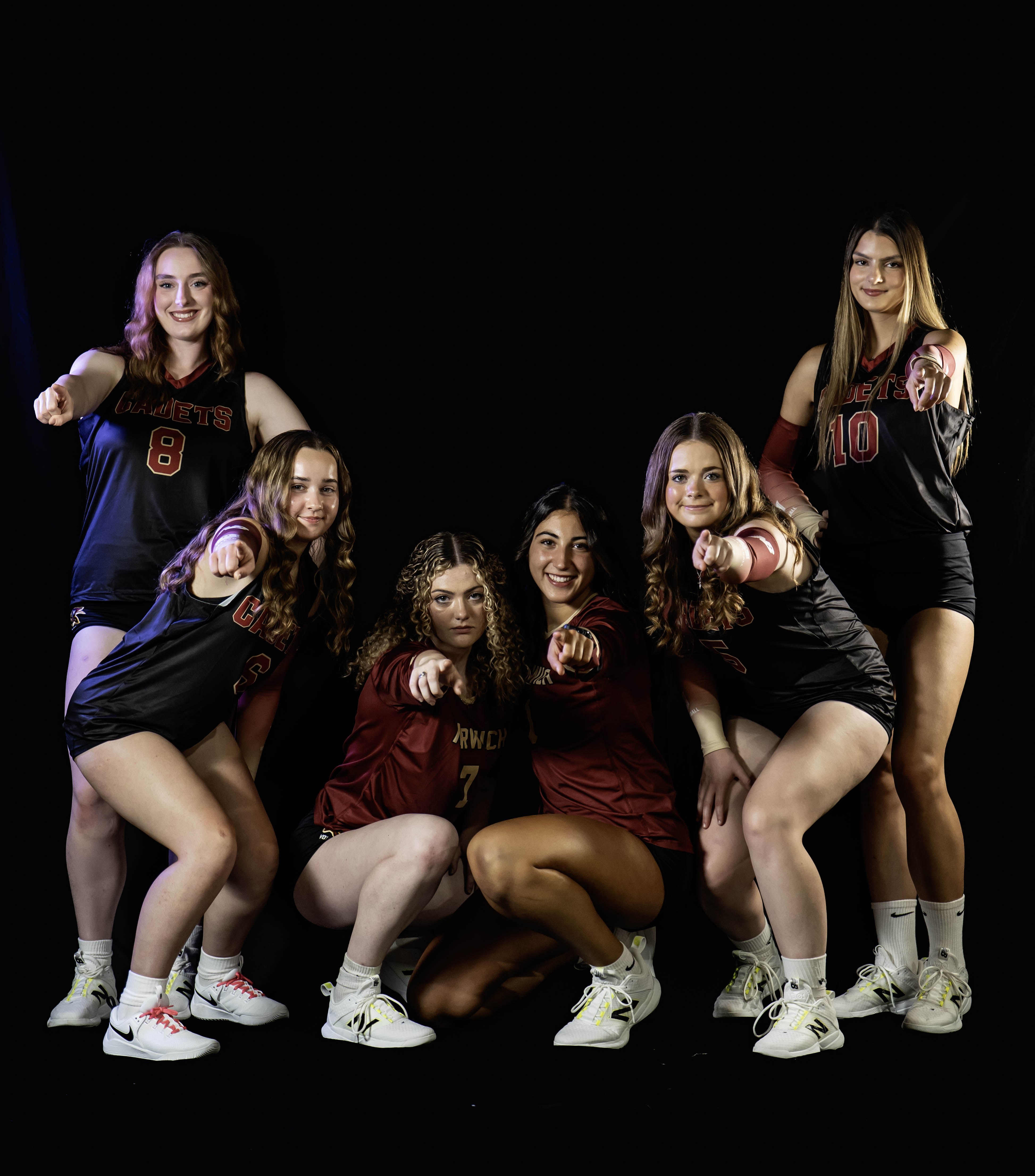 Volleyball players pose against a black background.
