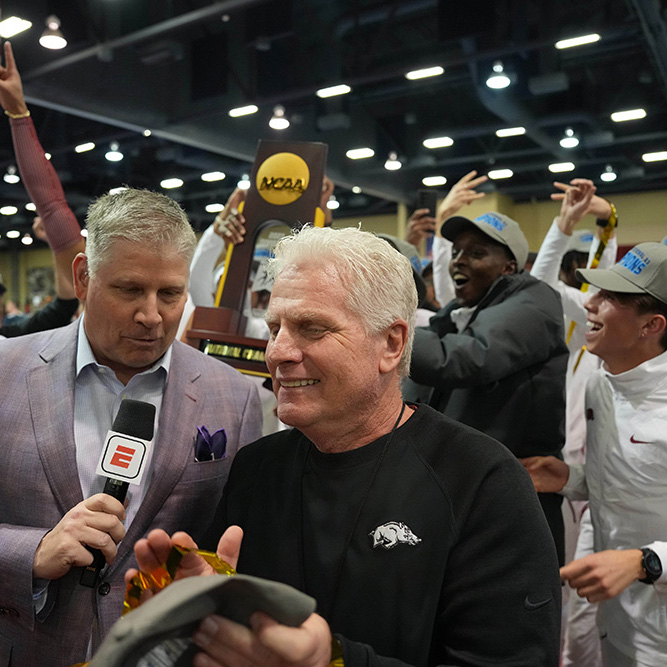 A man celebrates with his team as an ESPN reporter interviews him.