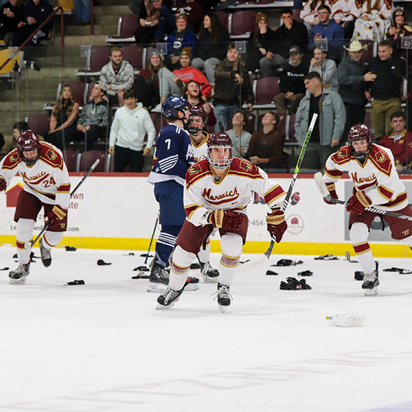 Norwich Mens Hockey cadets skate on the ice after scoring a goal, the ice littered with donated socks