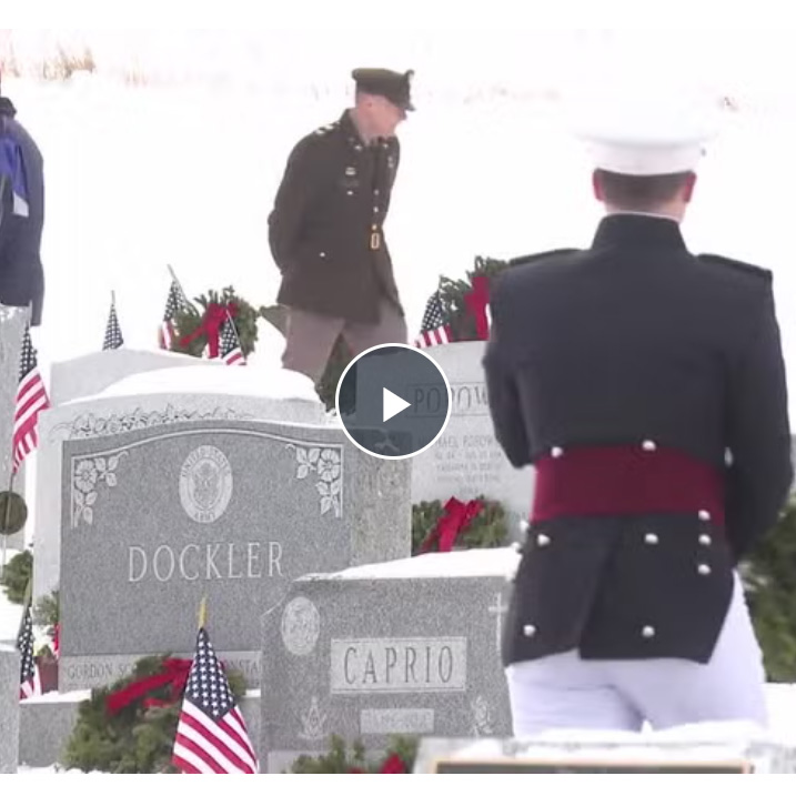 Soldiers walk through a snow-covered cemetery.