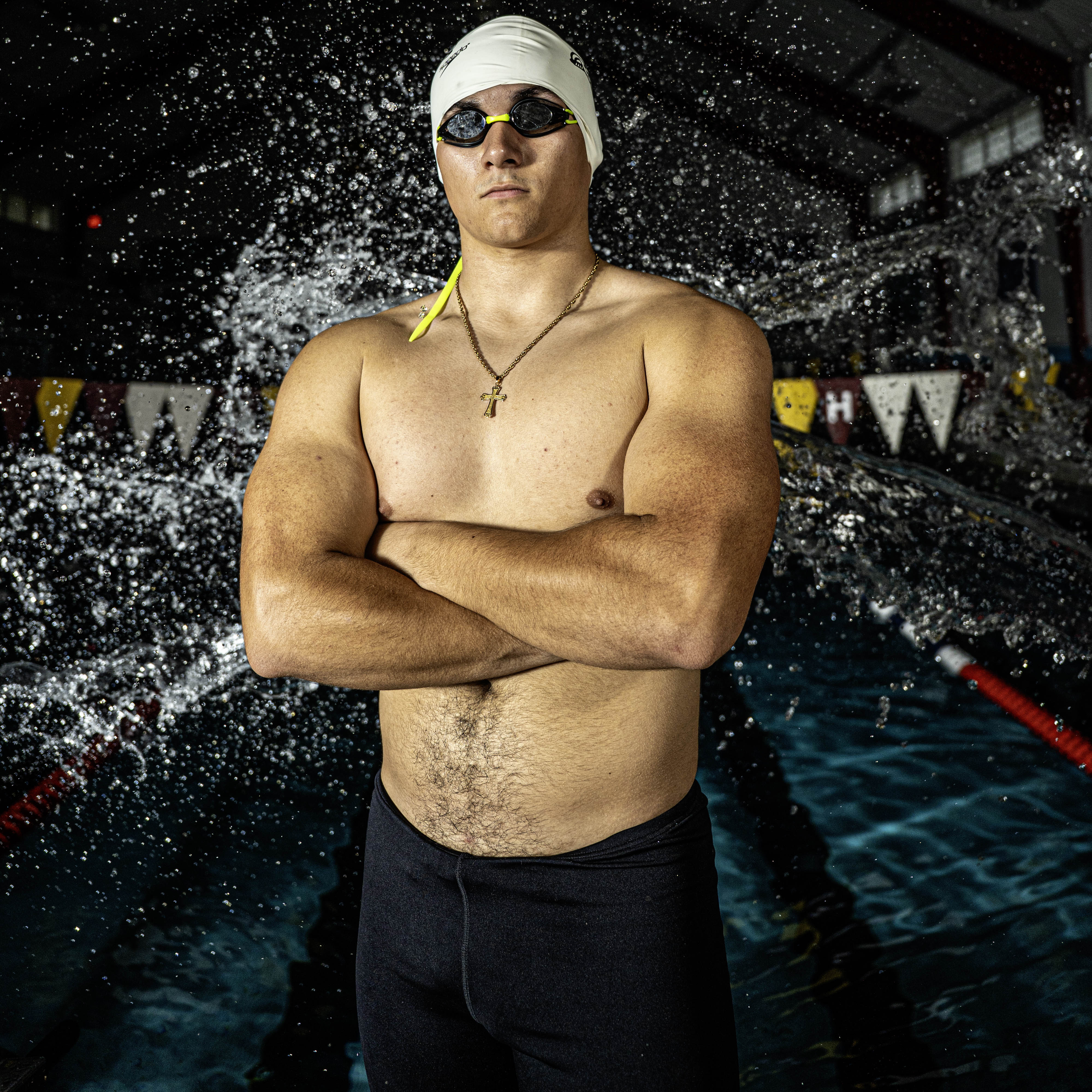A swimmer takes a posed shot with water splashing behind him.