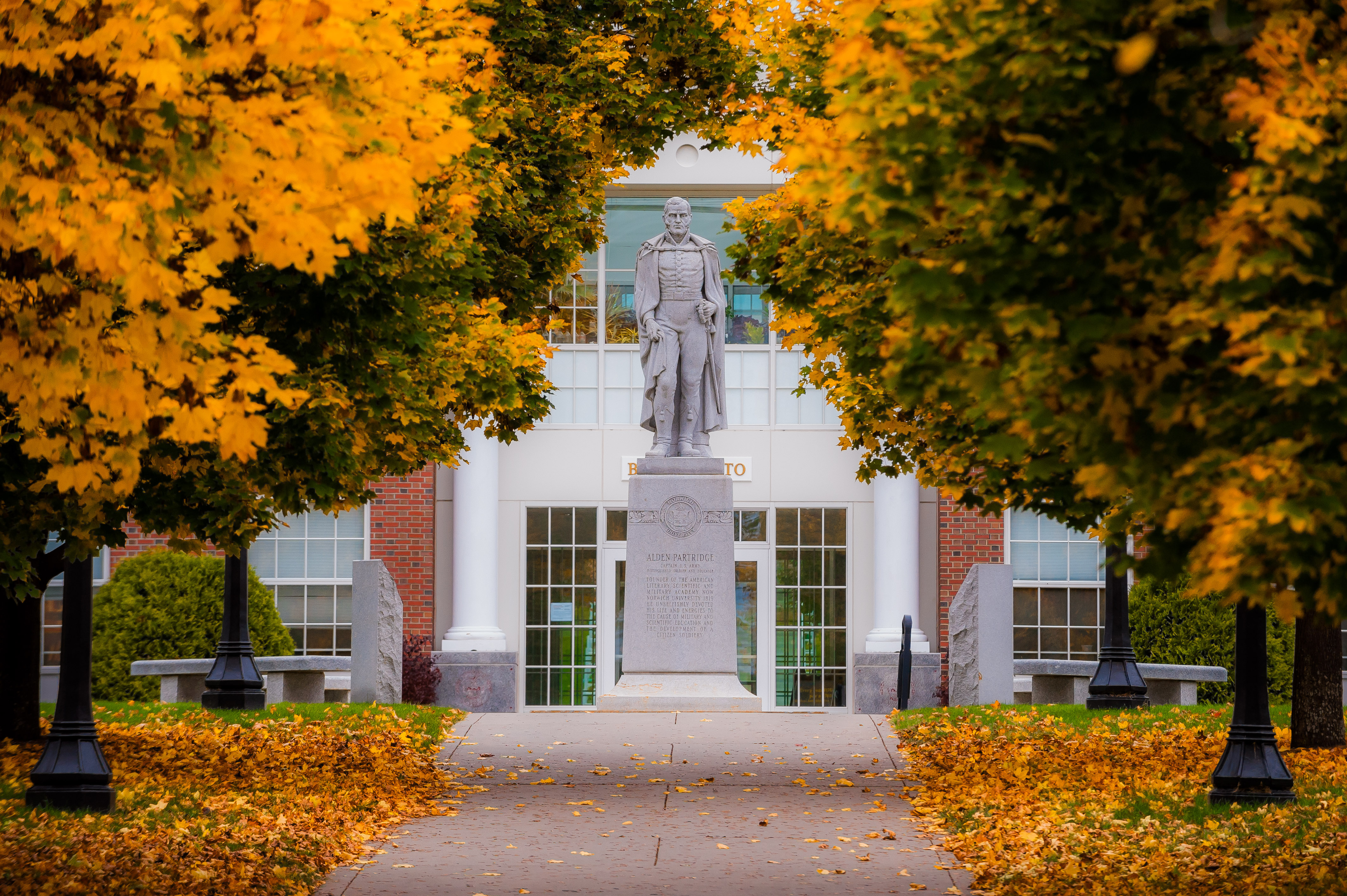 Statue of Captain Alden Partridge framed by vibrant autumn foliage, located at Norwich University.