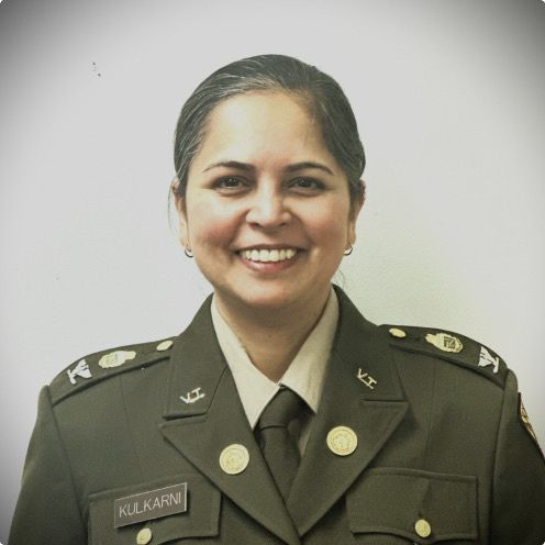 A person in military uniform smiles in formal portrait.