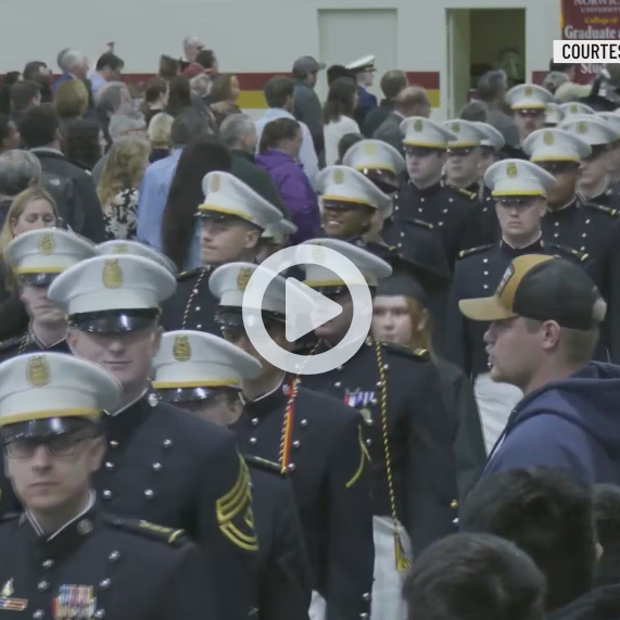 A group of cadets stand in uniform while in line at an event.
