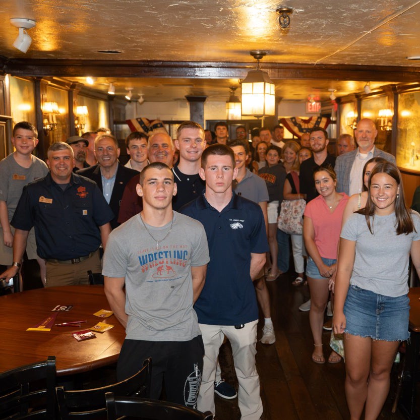 A large group poses together inside a wood-paneled room.