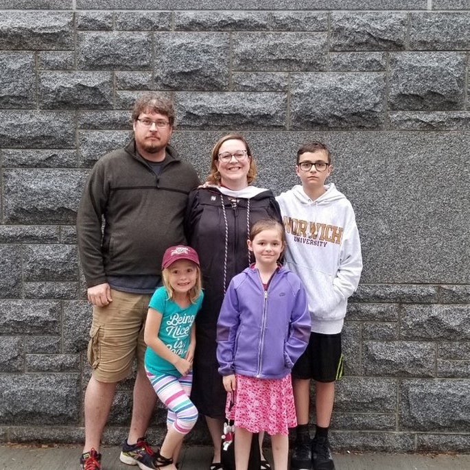Shannon Murphy poses with four people in front of a gray stone wall.