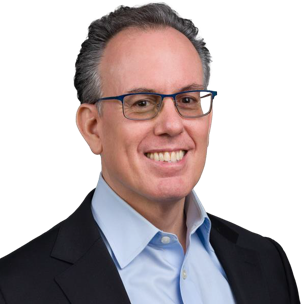 Portrait of a person wearing glasses, a dark blazer, and a light blue collared shirt.