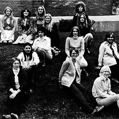 A group of people pose together on a grassy slope in a black-and-white photograph.