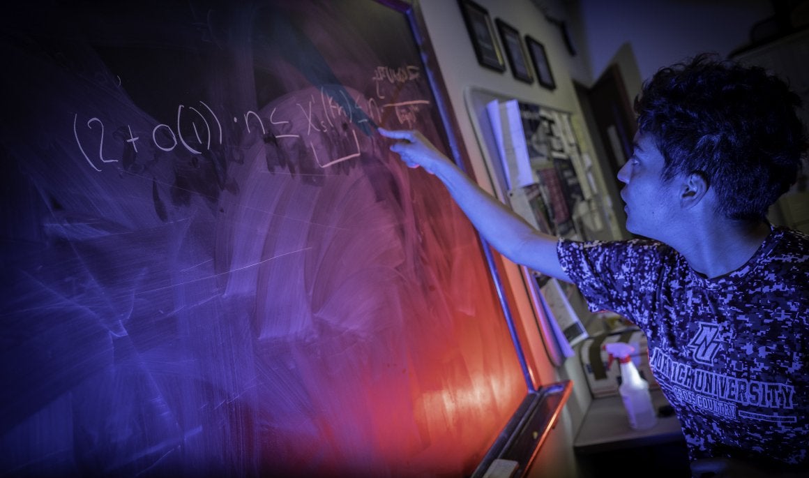 Student writing problem on chalkboard