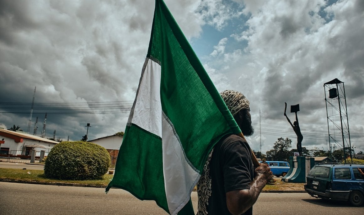 Photo of a man holding the Nigerian flag