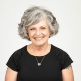 Individual in black blouse wearing a necklace. Headshot photo of Teri-Gene Conlin against a white background