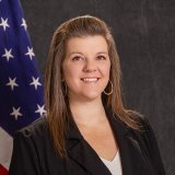 Vanessa Middleton profile image in a black blazer and white top standing in front of a U.S. flag and dark backdrop.