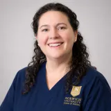 Person wearing glasses and navy Norwich School of Nursing scrubs.