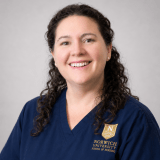 Person wearing glasses and navy Norwich School of Nursing scrubs.