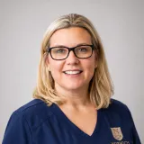Person wearing glasses and navy Norwich University School of Nursing scrubs.