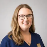 Person wearing glasses and navy Norwich University School of Nursing scrubs.