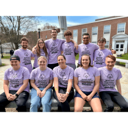 Group of students wearing matching purple t-shirts with Special Olympics Vermont 2025 logos, posing outdoors in front of a building with columns.