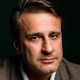 Close-up portrait of Simon Shuster against a dark background.