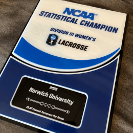 The NCAA Statistical Champion plaque lays on a counter, offset slightly.