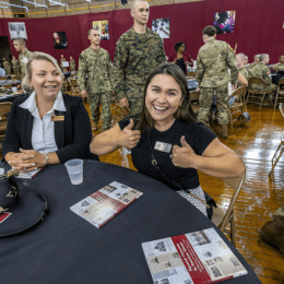 A Norwich student grins and gives two thumbs up during the First Contact event as a group of cadets walks behind her.