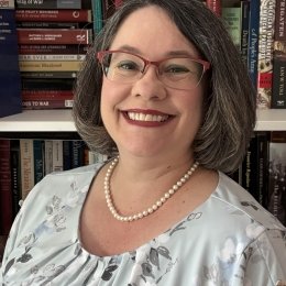A standard professional headshot of Lisa Mundey in front of a bookcase.