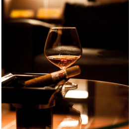 An image of a cigar and a glass of liquor on a table
