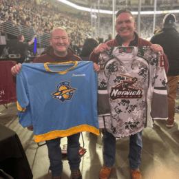 An image of two NU Alumni holding hockey jerseys, for the Atlanta Gladiators and the Norwich Cadets