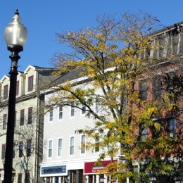 Three buildings are seen behind an older street lamp. "Architectural Detail - West Broadway - South Boston - MA - USA - 02 (52485266226)" by Adam Jones from Kelowna, BC, Canada is licensed under CC BY 2.0.