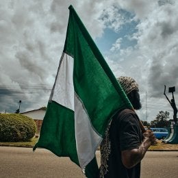 Photo of a man holding the Nigerian flag