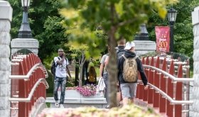 Norwich University students walking across the alumni bridge on campus.