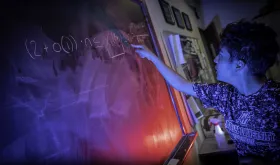 Student writing problem on chalkboard