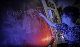 Student writing problem on chalkboard