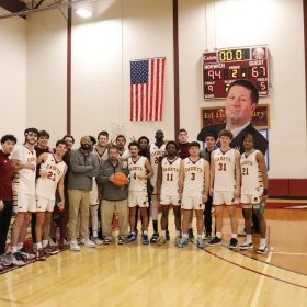 Norwich University 2025 Men's Basketball Team and Coaches celebrating head coach Paul Booth's 400th-career victory.