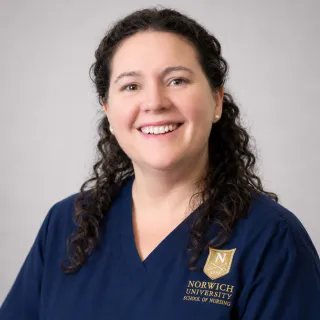 Person wearing glasses and navy Norwich School of Nursing scrubs.