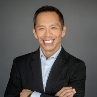Hansen in suitcoat and blue shirt with arms crossed