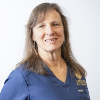 A person in a blue shirt poses against a plain white background.