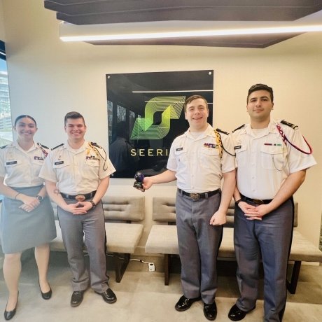 Isabella Ross, Jayden LaVecchia, Brendan Coyne, and Ahmed Mohammad stand in front of the Seerist logo on the wall in Seerist HQ; LaVecchia is displaying the trophy in his right hand.
