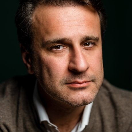 Close-up portrait of Simon Shuster against a dark background.