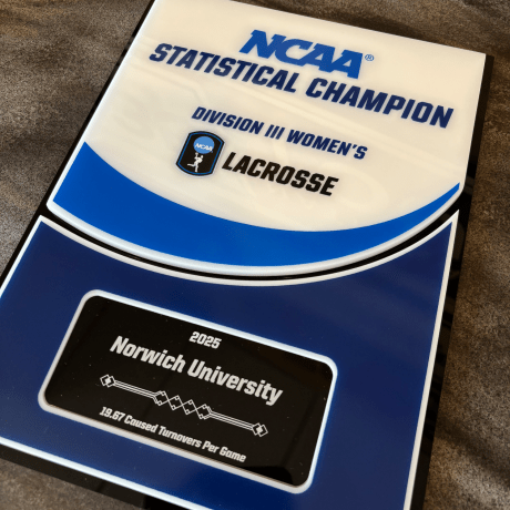 The NCAA Statistical Champion plaque lays on a counter, offset slightly.