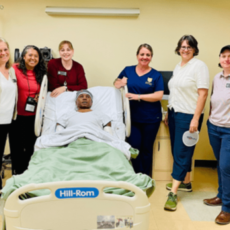 (Left to Right) Jennifer Coutu, Rea Colby, Janie Szalajeski-Hull, Amy Martone, Olga Ryan, and Cindy Freudenthal pose with a high-fidelity 3G manikin, Thomas, in one of the acute care hospital rooms located in the School of Nursing Clinical Simulation Center.