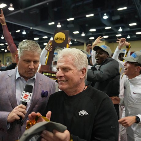 A man celebrates with his team as an ESPN reporter interviews him.