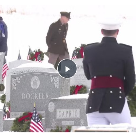 Soldiers walk through a snow-covered cemetery.